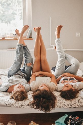women lying in bed with their legs in the air 