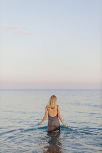 woman in brown dress standing on sea shore