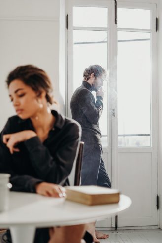 a man smoking at the back of a woman 