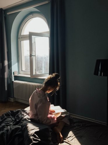 woman sitting while reading a book 