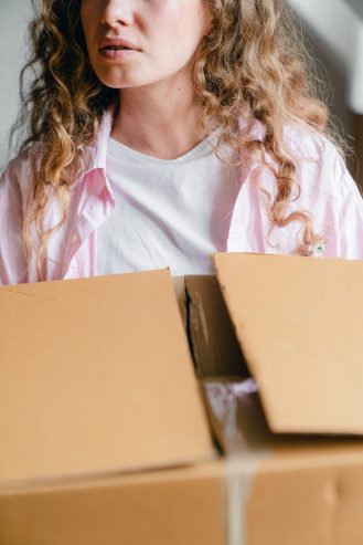 crop serious young lady carrying carton box at home