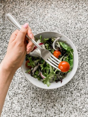 person eating tomato from salad