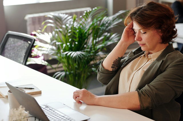 a corporate woman holding her head 