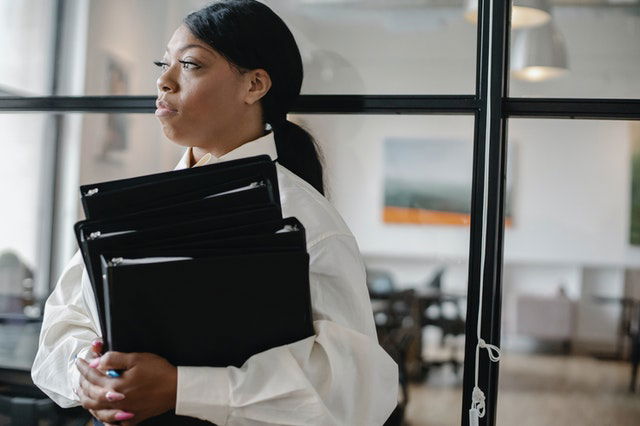 black woman carrying documents in the office