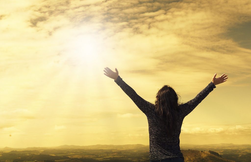 woman raising both hands to the sky 