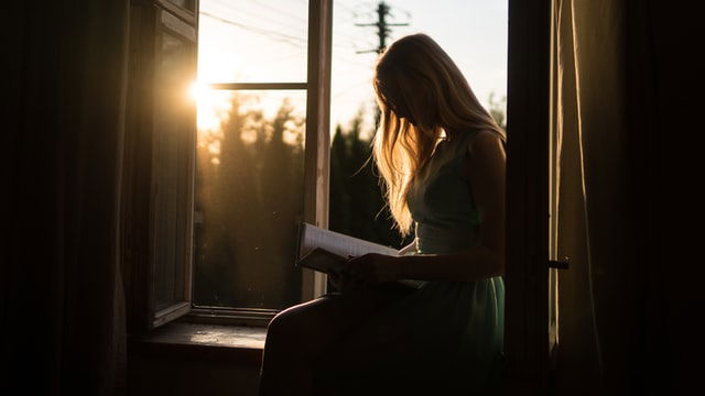 woman reading a book at the window
