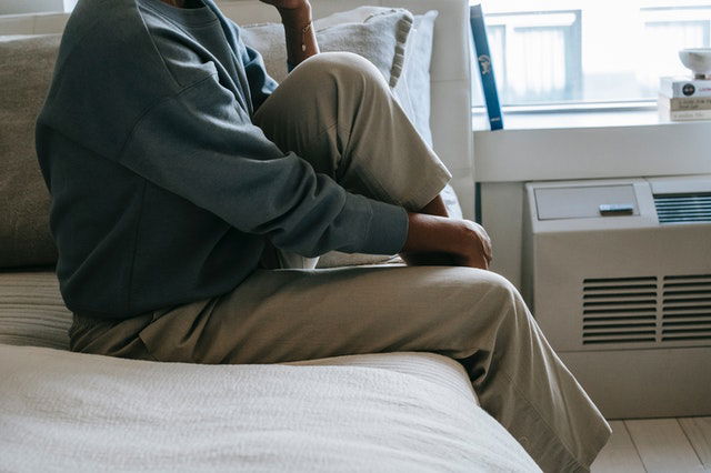 African American woman sitting on bed alone 