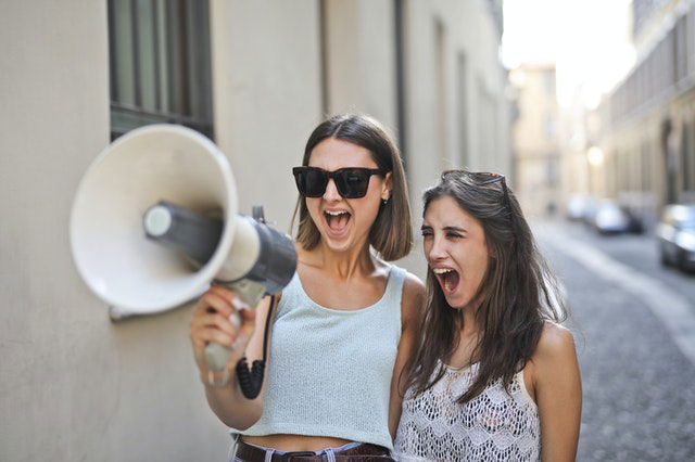 cheerful women screaming into loudspeaker 
