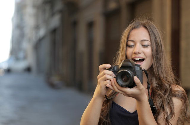 woman in black tank top holding a black DSLR 