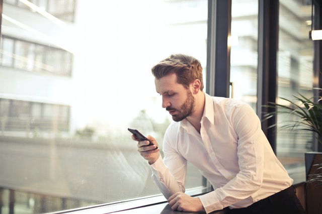 man near the window texting 