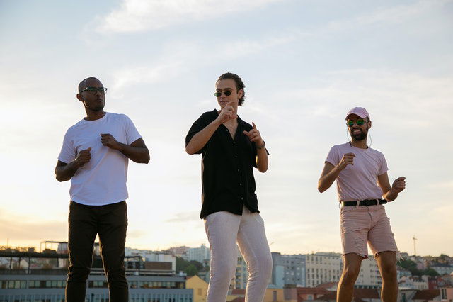 young diverse guys dancing on building roof during party