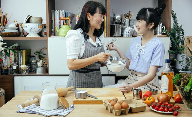 Asian mother and daughter happily discussing recipe at the kitchen 