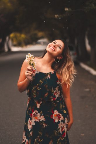 woman wearing a floral dress holding a flower 