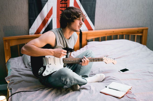 man in gray tank top playing guitar 