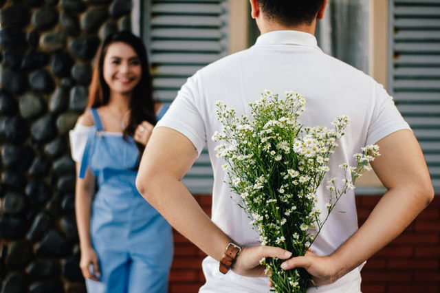 man surprising a woman with flowers 