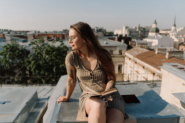 woman in brown and black stripe long sleeve shirt sitting on gray concrete bench