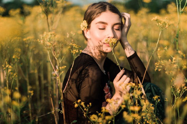 woman smiling while holding a yellow flower 