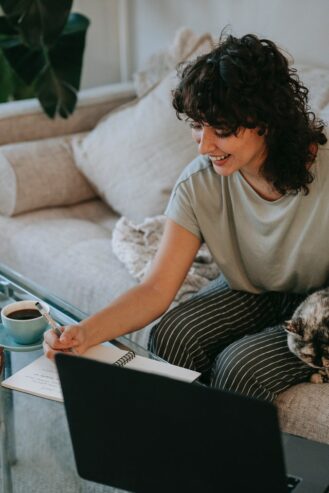 cheerful young ethnic woman taking notes