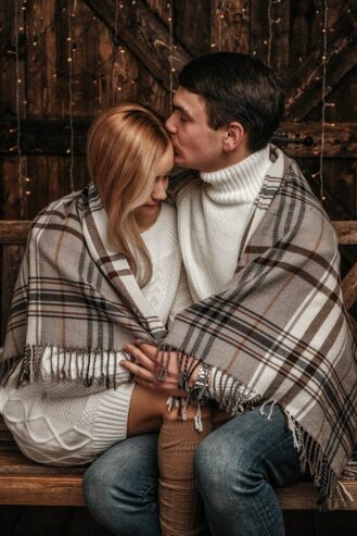 romantic couple cuddling and kissing on wooden bench